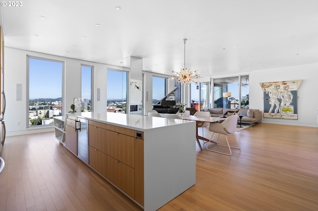 kitchen featuring decorative light fixtures, wine cooler, a chandelier, a large island, and light hardwood / wood-style flooring