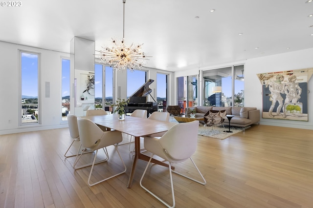 dining space with an inviting chandelier, expansive windows, and light hardwood / wood-style flooring