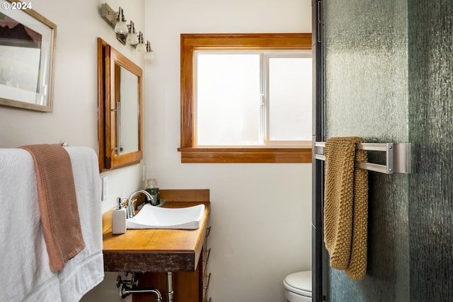 bathroom with toilet, sink, and a shower with door