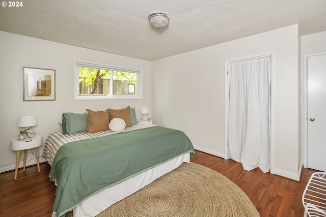 bedroom featuring a textured ceiling and dark hardwood / wood-style flooring