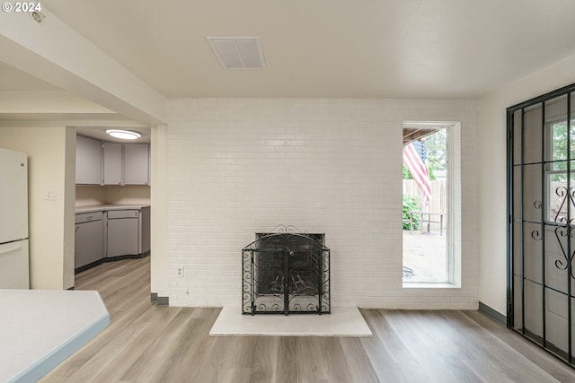 unfurnished living room featuring light hardwood / wood-style flooring and brick wall