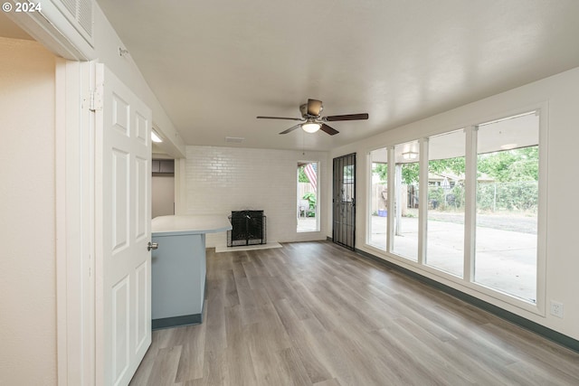 unfurnished living room featuring a fireplace, plenty of natural light, ceiling fan, and light wood-type flooring