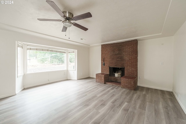 unfurnished living room with ceiling fan, light hardwood / wood-style floors, and a brick fireplace