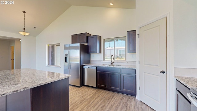 kitchen featuring pendant lighting, high vaulted ceiling, sink, light stone countertops, and stainless steel appliances