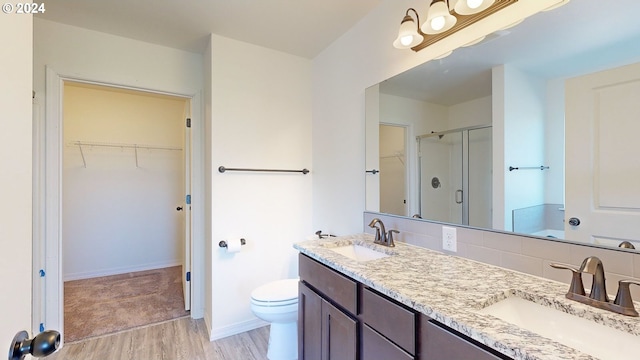 bathroom featuring wood-type flooring, vanity, toilet, and walk in shower