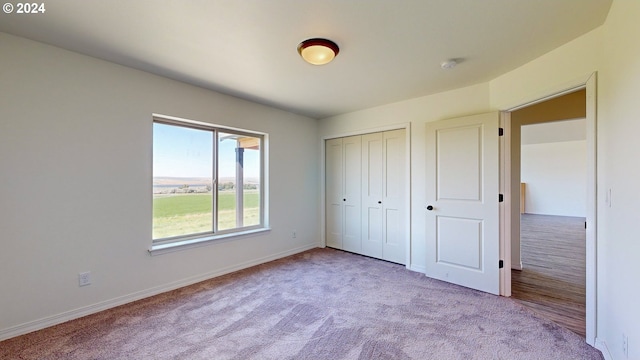 unfurnished bedroom featuring a closet and light colored carpet