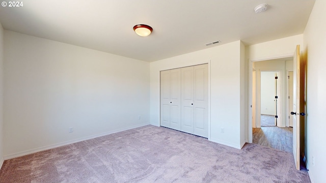 unfurnished bedroom with light colored carpet and a closet