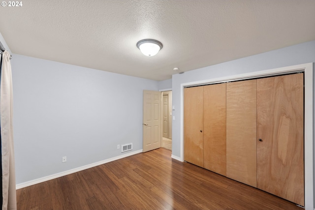 unfurnished bedroom with a closet, a textured ceiling, and hardwood / wood-style floors