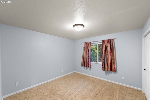 carpeted empty room with a textured ceiling