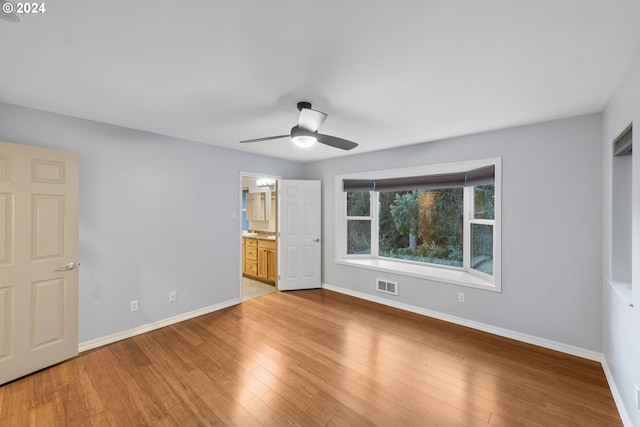 unfurnished bedroom with ensuite bath, light wood-type flooring, and ceiling fan