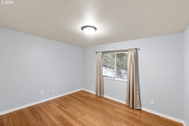 spare room featuring a textured ceiling and light wood-type flooring