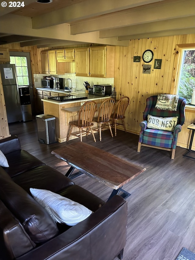 living room featuring beam ceiling, wood walls, sink, and dark wood-type flooring