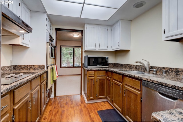 kitchen with appliances with stainless steel finishes, light hardwood / wood-style floors, white cabinetry, and sink