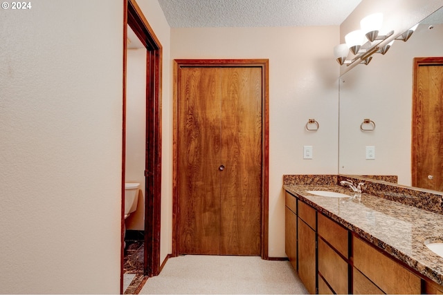 bathroom featuring vanity, a textured ceiling, and toilet