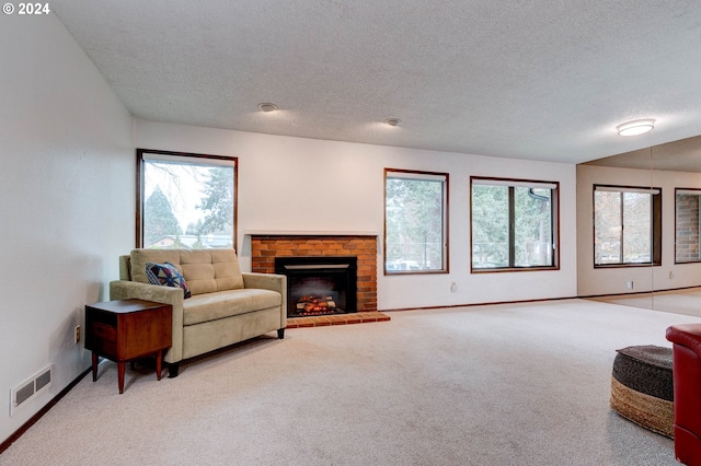 carpeted living room with a textured ceiling, plenty of natural light, and a fireplace