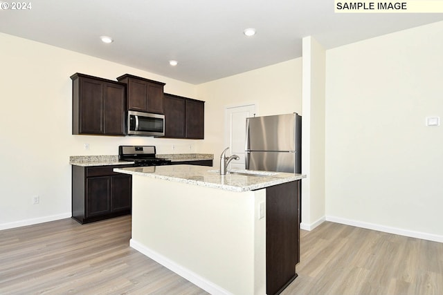 kitchen with sink, dark brown cabinets, a kitchen island with sink, stainless steel appliances, and light hardwood / wood-style floors