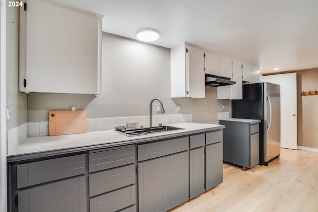 kitchen featuring gray cabinetry, white cabinetry, sink, light hardwood / wood-style flooring, and stainless steel fridge