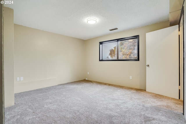 spare room featuring light carpet and a textured ceiling