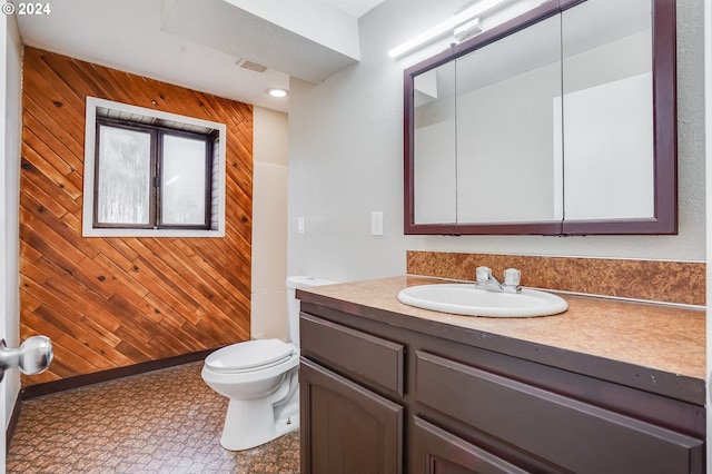 bathroom with vanity, toilet, and wood walls