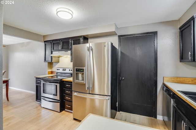 kitchen with light hardwood / wood-style floors, a textured ceiling, and appliances with stainless steel finishes