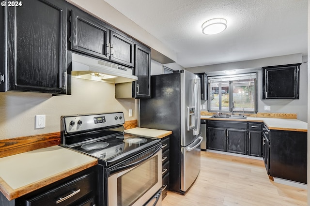 kitchen with sink, light wood-type flooring, a textured ceiling, and appliances with stainless steel finishes