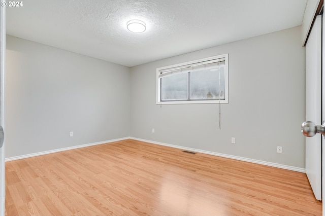 empty room with light hardwood / wood-style floors and a textured ceiling