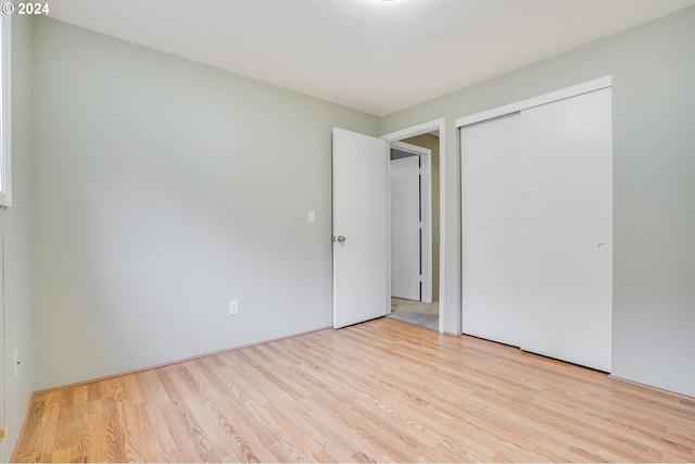 unfurnished bedroom featuring a closet, a textured ceiling, and light hardwood / wood-style flooring