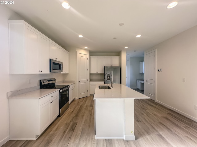 kitchen featuring a center island with sink, light wood-type flooring, white cabinetry, and appliances with stainless steel finishes