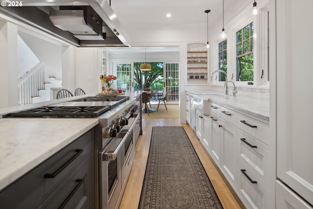 kitchen with light wood-type flooring, white cabinetry, plenty of natural light, and range with two ovens