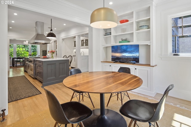 dining space featuring crown molding, light wood-type flooring, and a chandelier