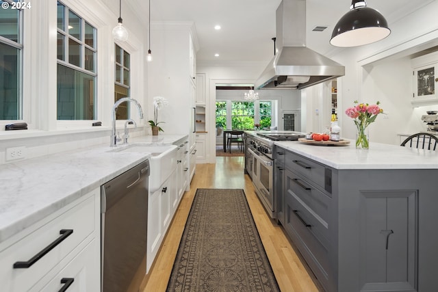 kitchen with appliances with stainless steel finishes, light stone counters, white cabinetry, and light hardwood / wood-style flooring