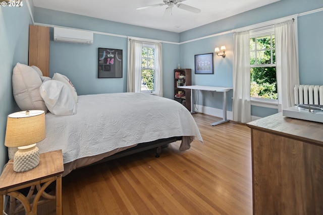 bedroom with ceiling fan, radiator, an AC wall unit, and light hardwood / wood-style flooring