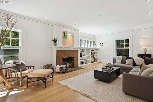 living room with crown molding, plenty of natural light, light wood-type flooring, and a brick fireplace