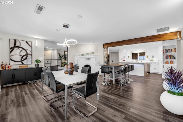 dining space featuring beamed ceiling, a chandelier, dark wood-type flooring, and sink