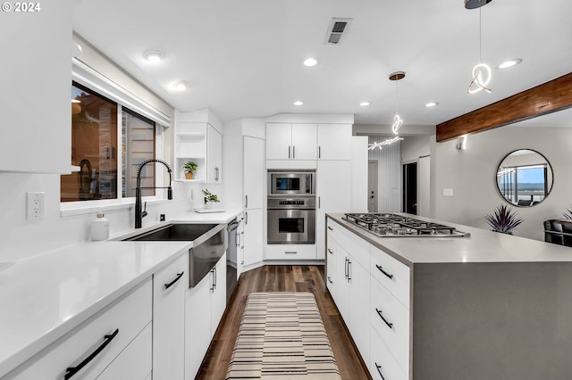 kitchen featuring beam ceiling, white cabinetry, sink, decorative light fixtures, and appliances with stainless steel finishes