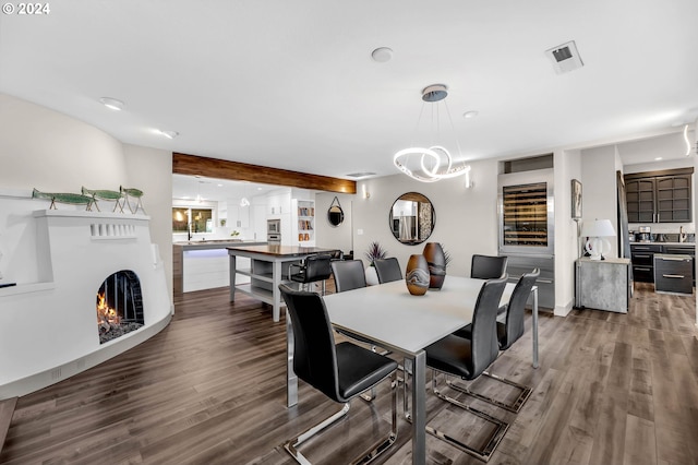 dining area featuring beamed ceiling, wood-type flooring, and a notable chandelier