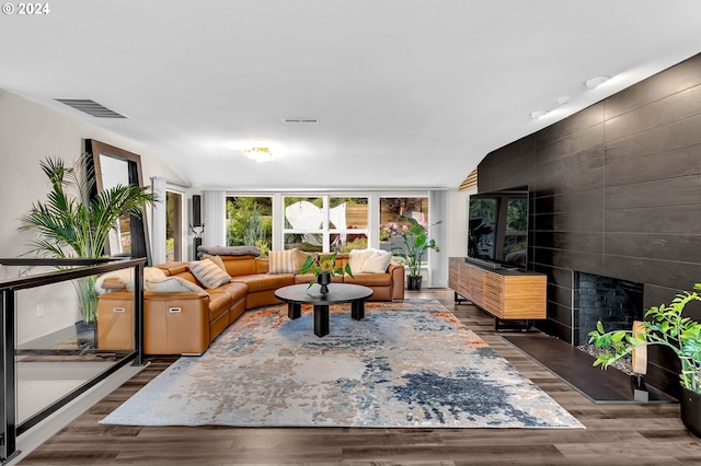 living room with a tile fireplace, dark hardwood / wood-style floors, and vaulted ceiling