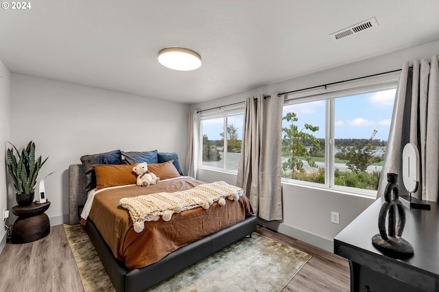 bedroom with hardwood / wood-style floors and multiple windows