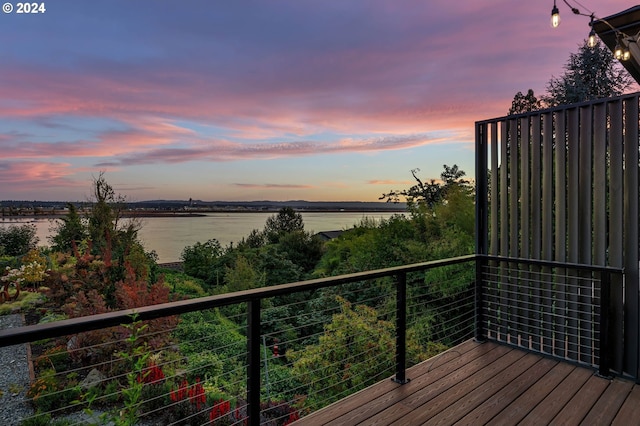 deck at dusk featuring a water view