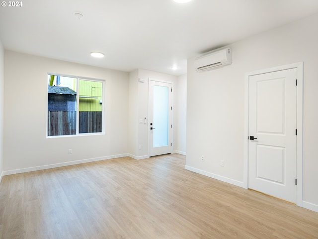 unfurnished room with a wall mounted air conditioner and light hardwood / wood-style floors