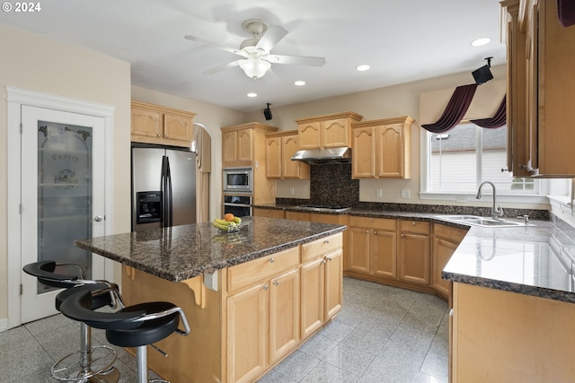 kitchen with ceiling fan, sink, a breakfast bar area, a kitchen island, and appliances with stainless steel finishes