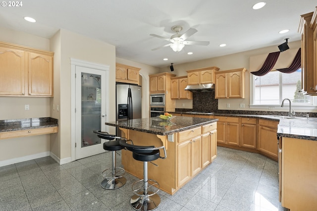 kitchen featuring dark stone countertops, sink, a kitchen island, and appliances with stainless steel finishes