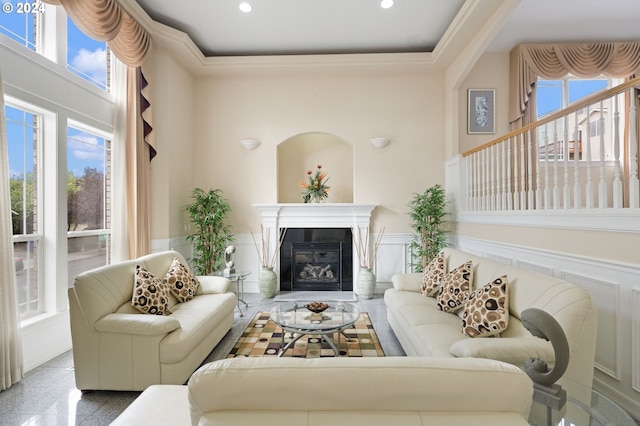 living room featuring a towering ceiling, crown molding, and a tiled fireplace