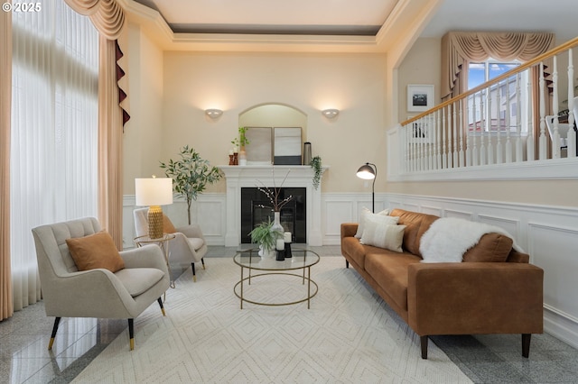 sitting room with a wainscoted wall, granite finish floor, a decorative wall, and a glass covered fireplace