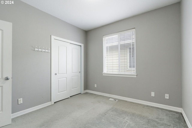 unfurnished bedroom with light carpet and a closet