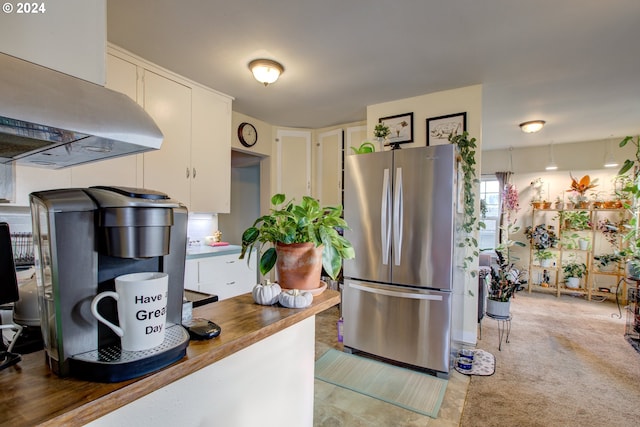 kitchen with white cabinetry, stainless steel fridge, butcher block counters, and island exhaust hood