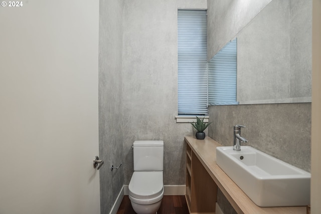 half bathroom with toilet, vanity, and wood finished floors