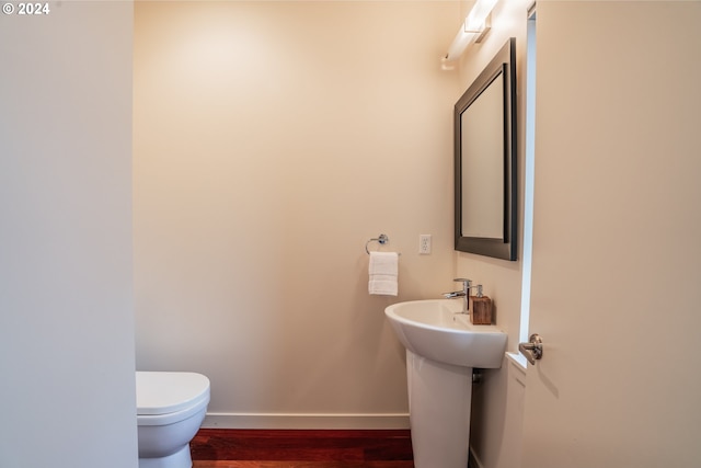 bathroom with toilet, wood finished floors, and baseboards