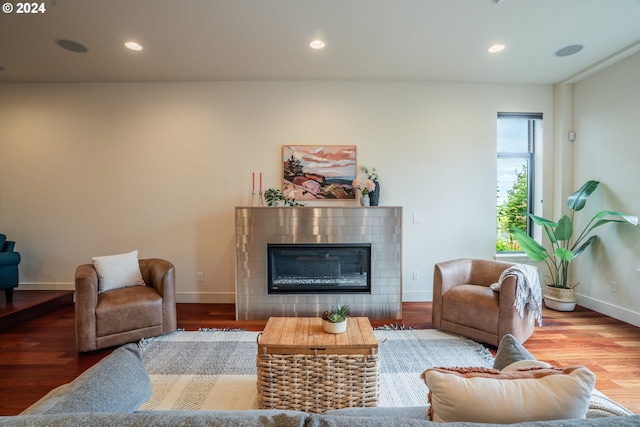 living room featuring a tiled fireplace, baseboards, recessed lighting, and wood finished floors