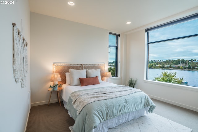 carpeted bedroom featuring baseboards, a water view, and recessed lighting